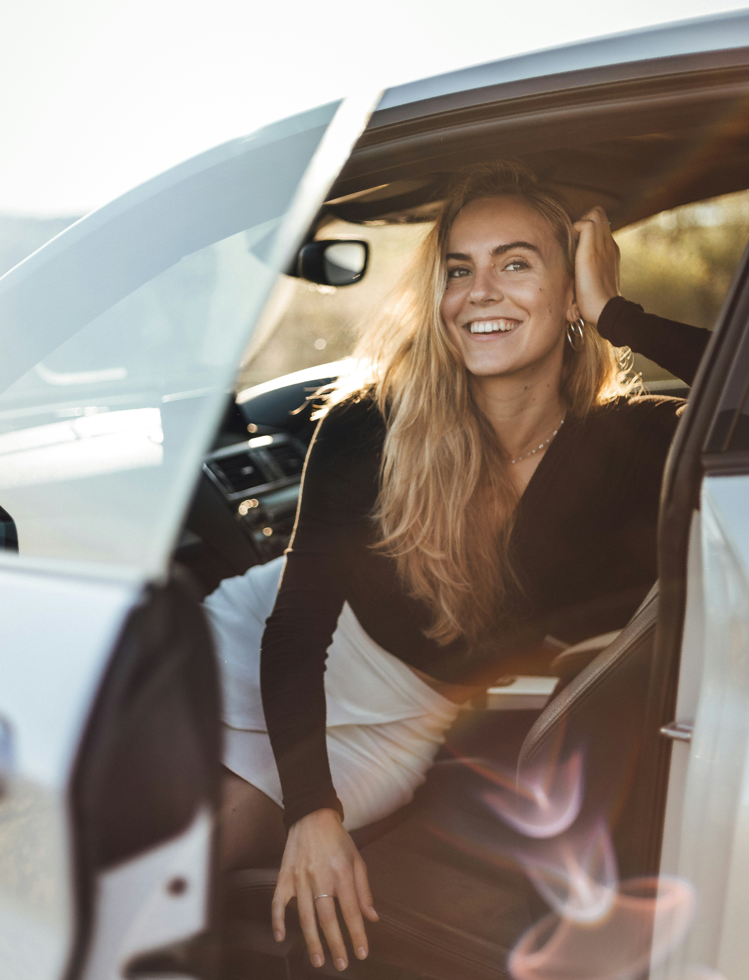 Smiling customer stepping out of her freshly valeted car at golden hour